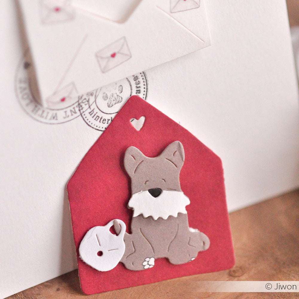 Ein Papierausschnitt mit einem süßen Hund und einem Napf auf einer roten Hausform, hergestellt mit Alexandra Renke Motivstanze Dies, mit Umschlägen im Hintergrund.