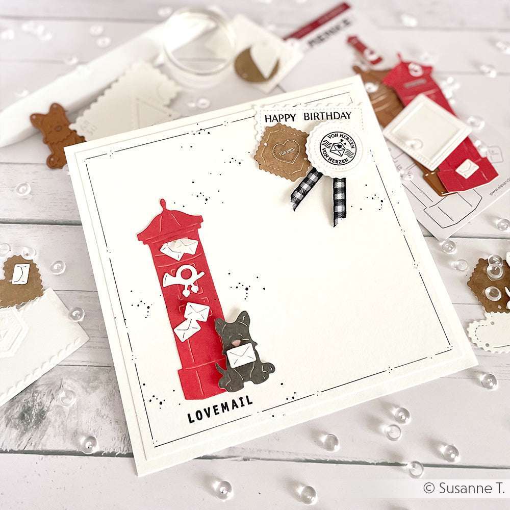 Handgefertigte Karte von Alexandra Renke mit einem roten Briefkasten, einer Katze und Buchstaben mit der Aufschrift Lovemail, verziert mit Designpapieren und DieCut-Systemen für extra kreatives Flair.
