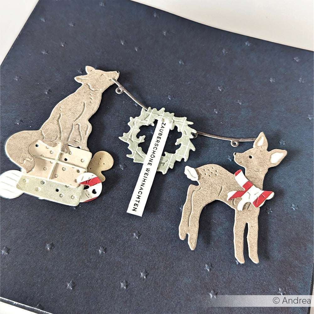 Die gestanzten Papierformen von Alexandra Renke - Fuchs, Rehkitz, Geschenke, Kranz und Zuckerstangen - sind auf einem dunklen, mit Schneeflockenpunkten verzierten Hintergrund zu sehen.