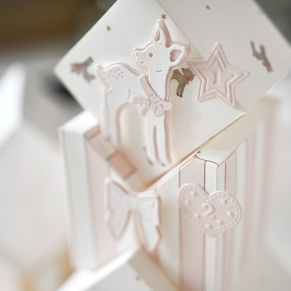 Nahaufnahme von pastellfarbenen Babyblöcken, die mit Schleifen, Sternen, Herzen und einem bezaubernden Hirschmotiv verziert sind, das von Motivstanze Rehkitz von Alexandra Renke inspiriert wurde.