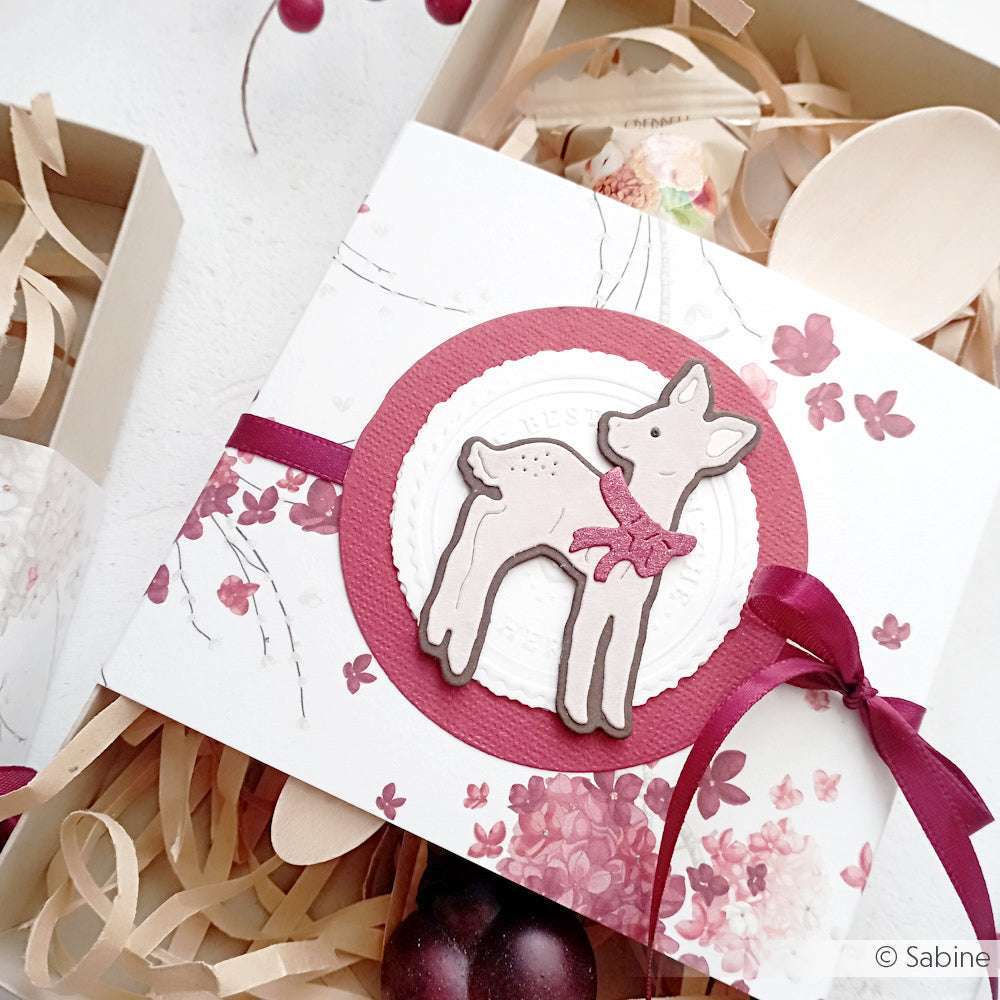 Geschenkbox mit einem niedlichen Hirschmotiv aus Alexandra Renkes Motivstanze Rehkitz, kastanienbraunem Band und floralen Akzenten - perfekt, um Ihre Lieblings Alexandra Renke Designpapiere inmitten von geschreddertem Papier zu präsentieren.