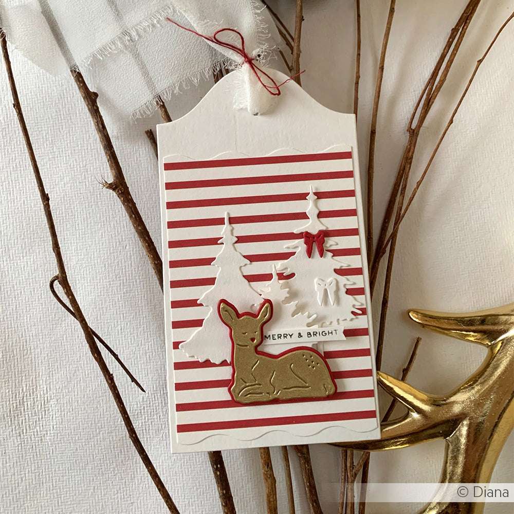 Geschenkanhänger mit roten Streifen, weißen Bäumen, einer Schleife und einem braunen Reh, hergestellt mit Alexandra Renke Designpapiere und Motivstanze Schicht Rehkitz 2 DieCut System, auf Zweigen.