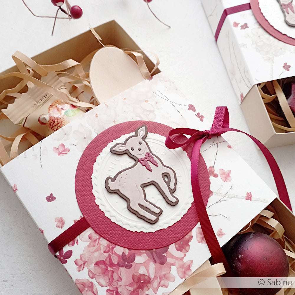 Geschenkkarton mit Blumenpapier, burgunderrotem Band und einem niedlichen Hirsch, der mit der Alexandra Renke Motivstanze Rehkitz ausgestanzt wurde, gefüllt mit Leckereien.