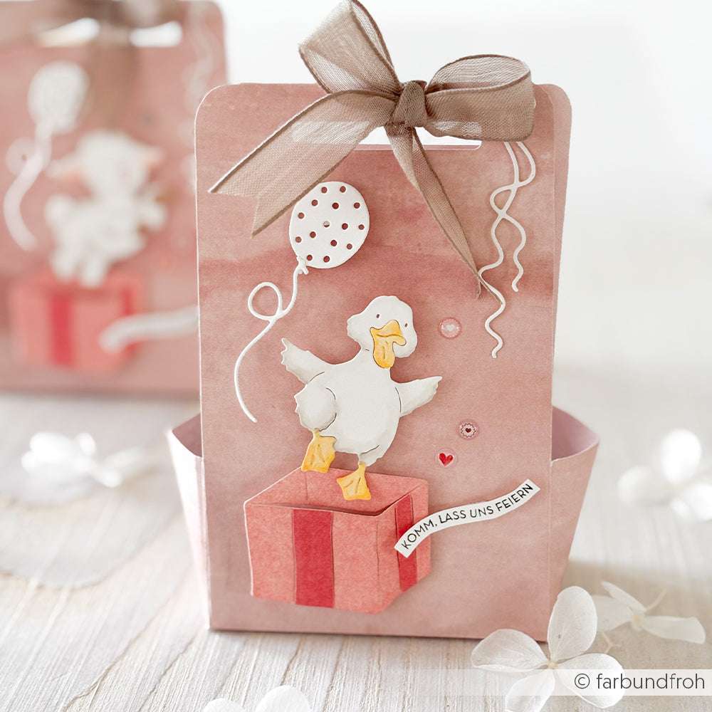 Rosa Geschenktüte mit Schleife, verziert mit einer Ente, Luftballons und einem deutschen Festtagsgruß - gebastelt mit den PAPPcut®ies von Alexandra Renke und der Motivstanze Begeisterte Entchen für zusätzlichen Charme.