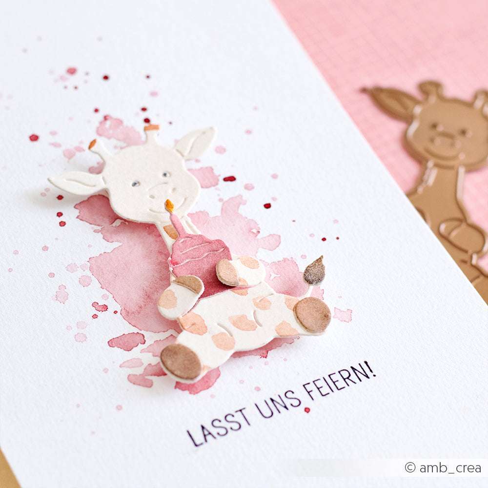 Handgemachte Giraffenkarte mit der Motivstanze Giraffe von Alexandra Renke, mit einem Cupcake, rosa Aquarellhintergrund und dem Text "LASST UNS FEIERN!" darunter.