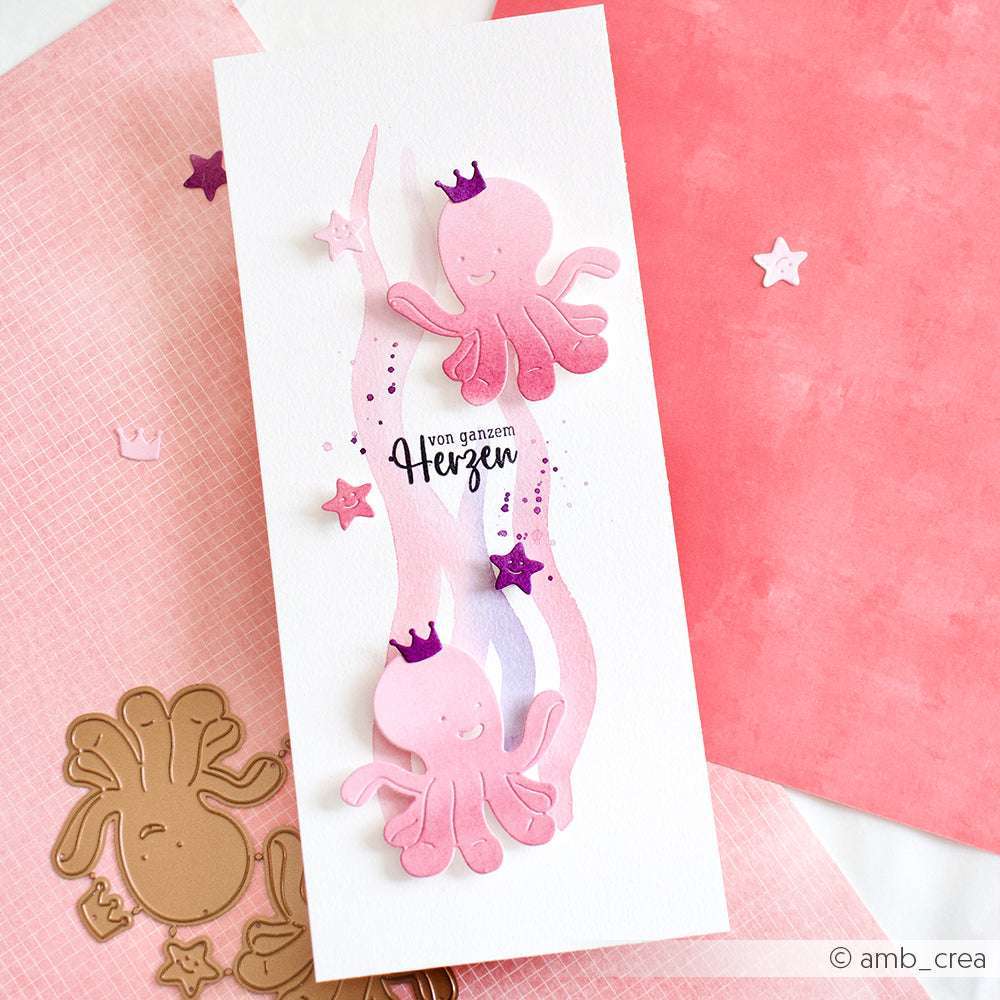 Handgefertigte Karte mit zwei rosafarbenen Kraken, die mit der Alexandra Renke Motivstanze Oktopus hergestellt wurden, verziert mit lila Kronen, deutschem Text und dekoriert mit Sternen und Herzen.