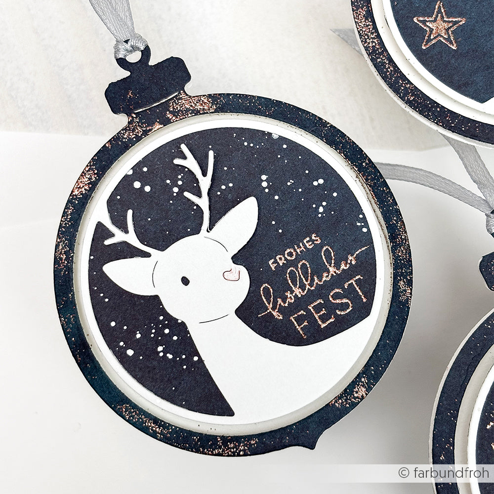 Alexandra Renke rundes Ornament mit weißem Rentier, Sternenhintergrund und "Frohes Fest" - ideal für Ihre Projekte mit Stanzsystemen oder in Kombination mit den Motivstanze Rentier.