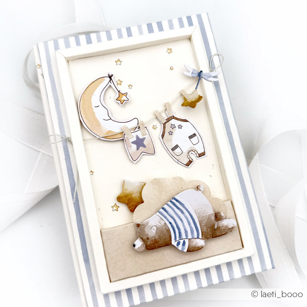 Ein niedlicher Bär im Schlafanzug schläft unter Sternen und dem Mond mit Hausdekor in einem gestreiften Rahmen - perfekt für einzigartige Basteleien mit Alexandra Renke Motivstanze Schlafgefährten oder DieCut Systemen.