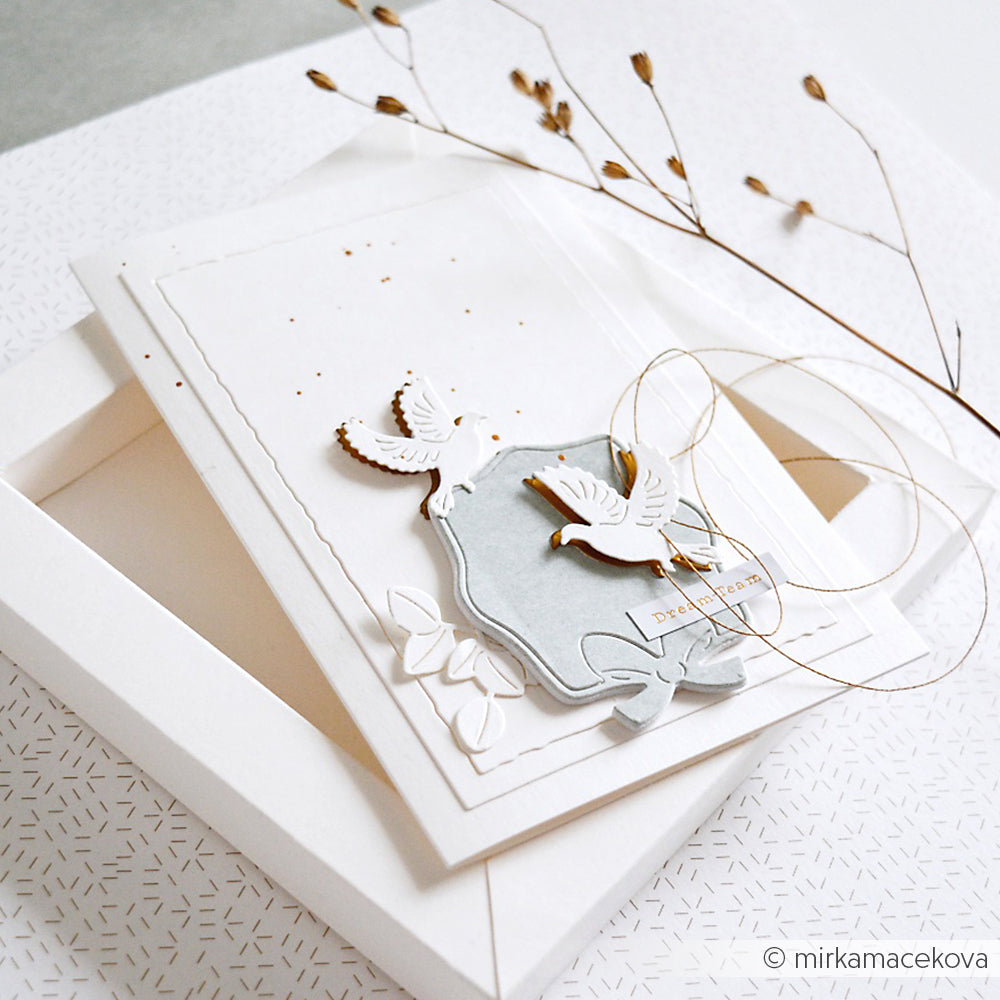 Elegante weiße Grußkarte von Alexandra Renke aus edlen Designpapieren mit geprägten Tauben (Motivstanze Tauben Trio), goldenen Akzenten, getrockneten Zweigen und einem passenden Umschlag.