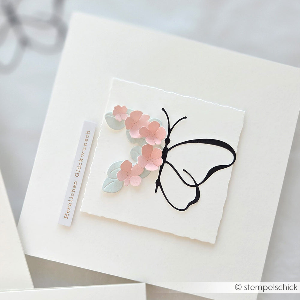 Handgefertigte Karte von Alexandra Renke mit einer Motivstanze Schmetterling und pastellrosa und grauen 3D-Blumen aus hochwertigen Designpapieren, veredelt mit einem deutschen Gruß auf der Seite.