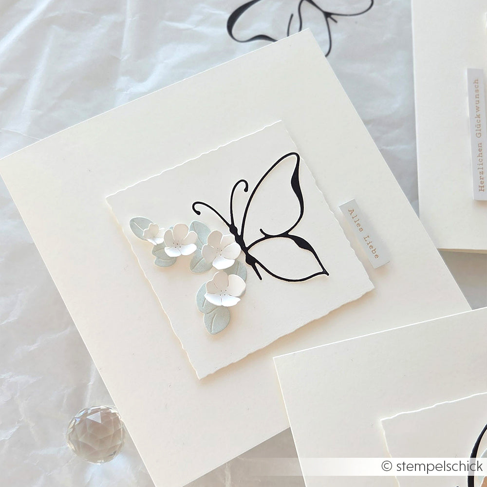 Handgemachte Karte von Alexandra Renke mit einem schwarzen Schmetterling und weißen 3D-Blumen auf weißem Designerpapier.