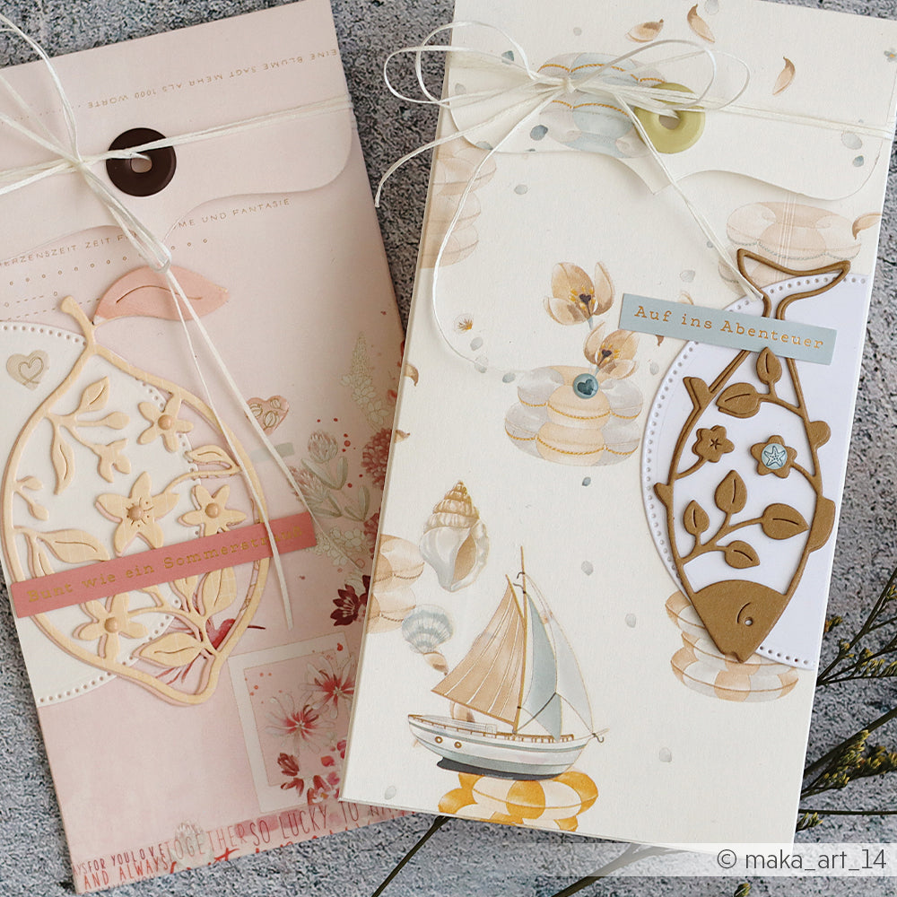 Zwei Grußkarten von Alexandra Renke mit Motiven aus der Welt des Segelsports und Muscheln, verziert mit Designpapier, Schleifen und Etiketten mit deutschem Text.
