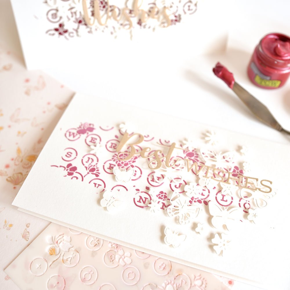 Handgefertigte Glückwunschkarte mit ausgestanzten Blumen, rosa Schablonenmustern und passendem Bastelmaterial – darunter die „Motivstanze Schmetterlinge“ von Alexandra Renke, Stanzformen und elegante Designpapiere – für eine ganz besondere Note.