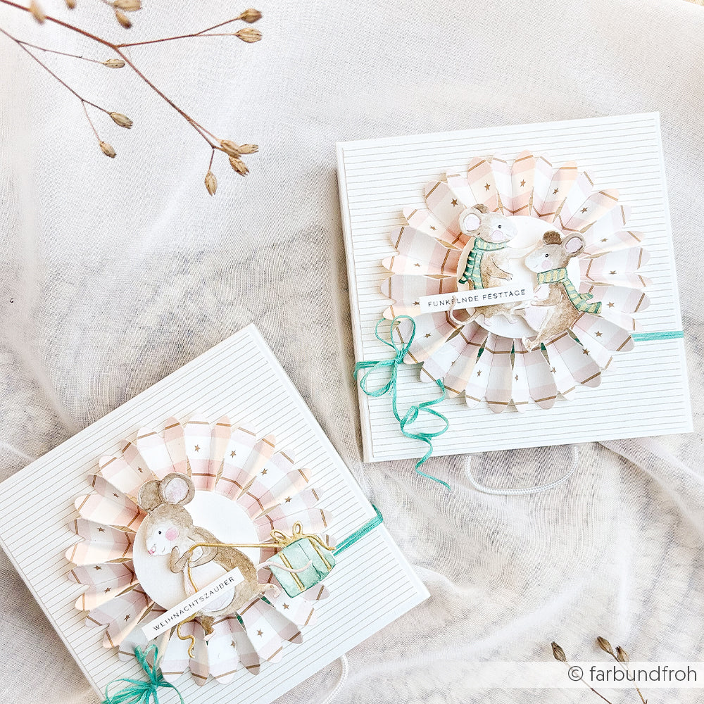 Zwei Geschenkboxen, verziert mit Papierrosetten und Papier mit Mausmotiven.