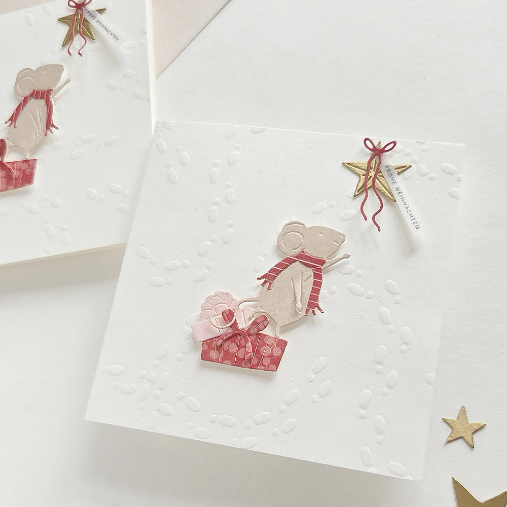 Zwei Weihnachtskarten mit einer Motivstanze Zauberhafte Maus, die unter einem Stern ein Geschenk in der Hand hält.