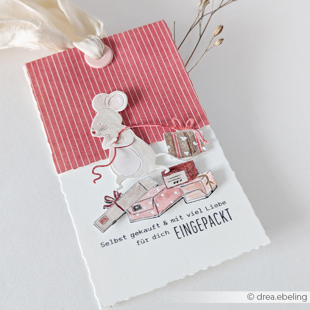 Ein Geschenkanhänger mit einer Geschenkemaus, die ein Geschenk hinter sich herzieht, und der Aufschrift: Selbst gekauft & eingepackt.