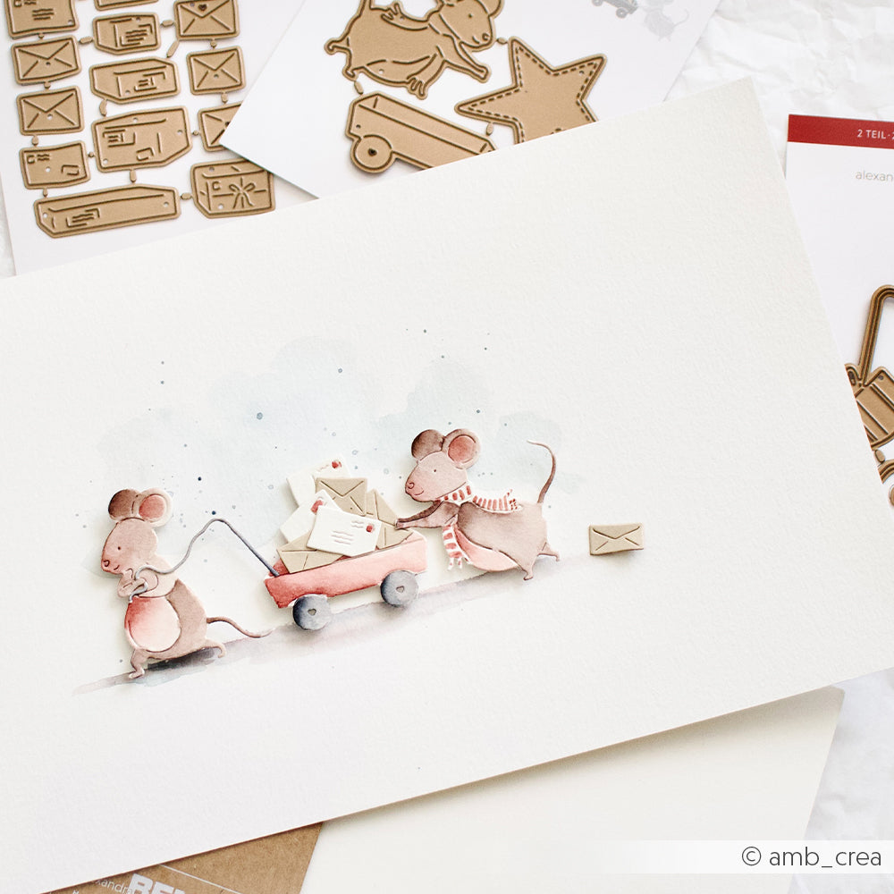 Aquarellillustration von zwei Mäusen, die einen roten Wagen ziehen, der mit Umschlägen für Motivstanzformen gefüllt ist.