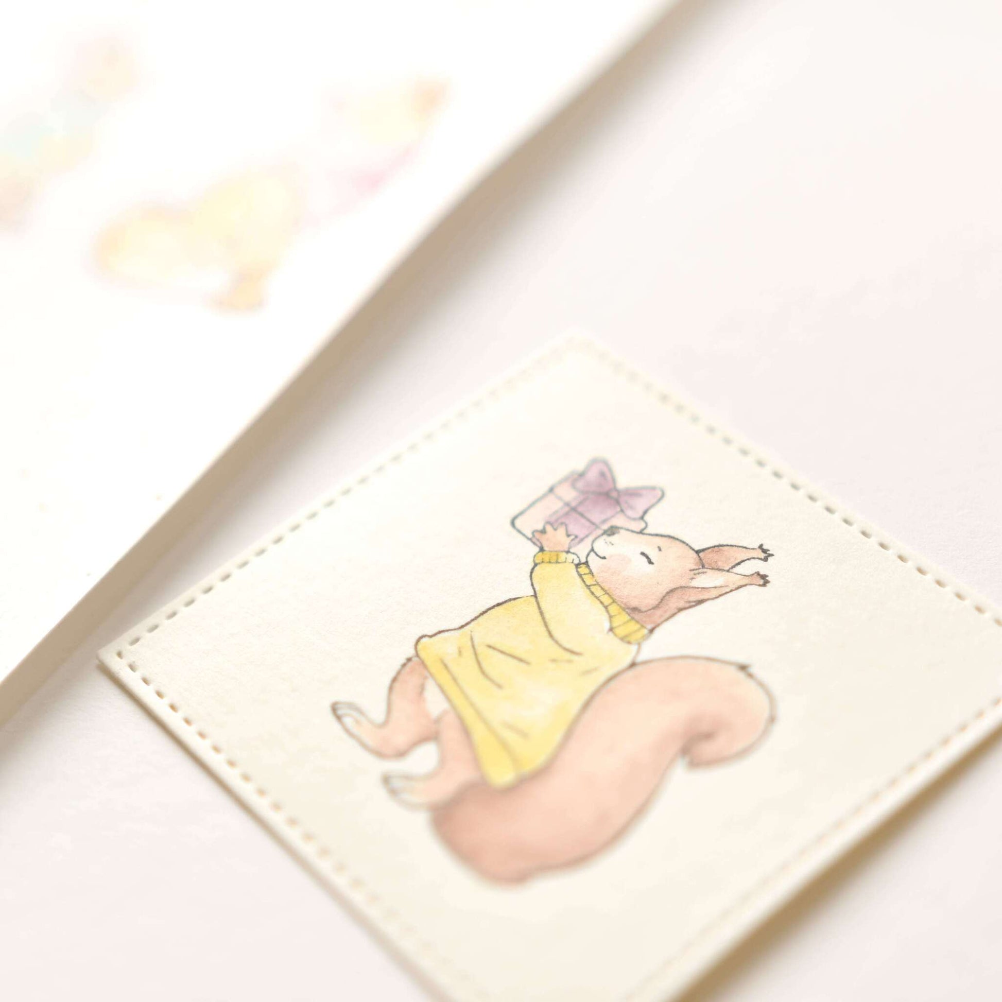 Eine charmante weiße quadratische Karte von Alexandra Renke mit der Zeichnung eines Eichhörnchens mit Geschenk in einem gelben Kleid - ideal als einzigartiger Holzstempel oder für Stempel Papierprojekte.