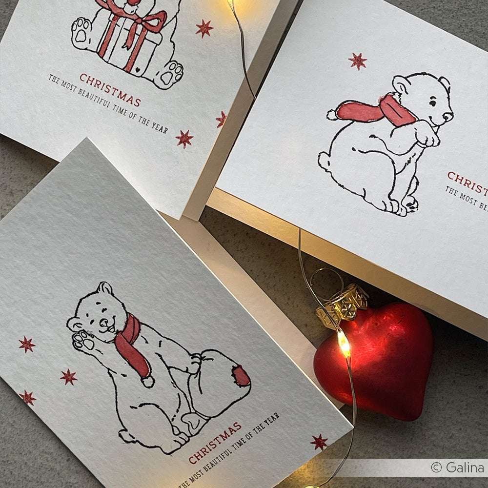 Drei Weihnachtskarten von Alexandra Renke mit Eisbären in roten Schals, Eisbärbaby Kaja-Motiven und festlichen Lichtern werden mit einem Herzschmuck präsentiert - eine reizvolle Weihnachtsszene für Stempelgummi/Holzstempel-Fans.