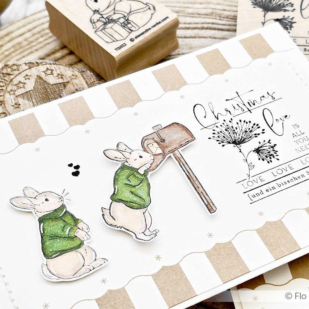Handgefertigte Karte von Alexandra Renke mit zwei Hasen in grünen Pullovern, von denen einer einen Brief verschickt, mit weihnachtlichen Stempelkissen-Drucken, Holzstempel-Akzenten und der liebenswerten Figur Hase Hoppel.