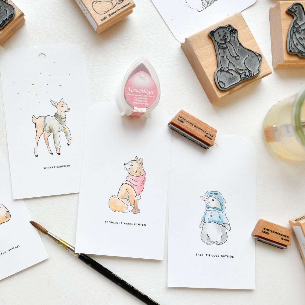 Handgemachte Tier-Grußkarten und Pinguin-Kiesel von Alexandra Renke, hergestellt mit Tinte, Pinsel, rosa Stempelkissen und Holzstempel auf weißem Untergrund.