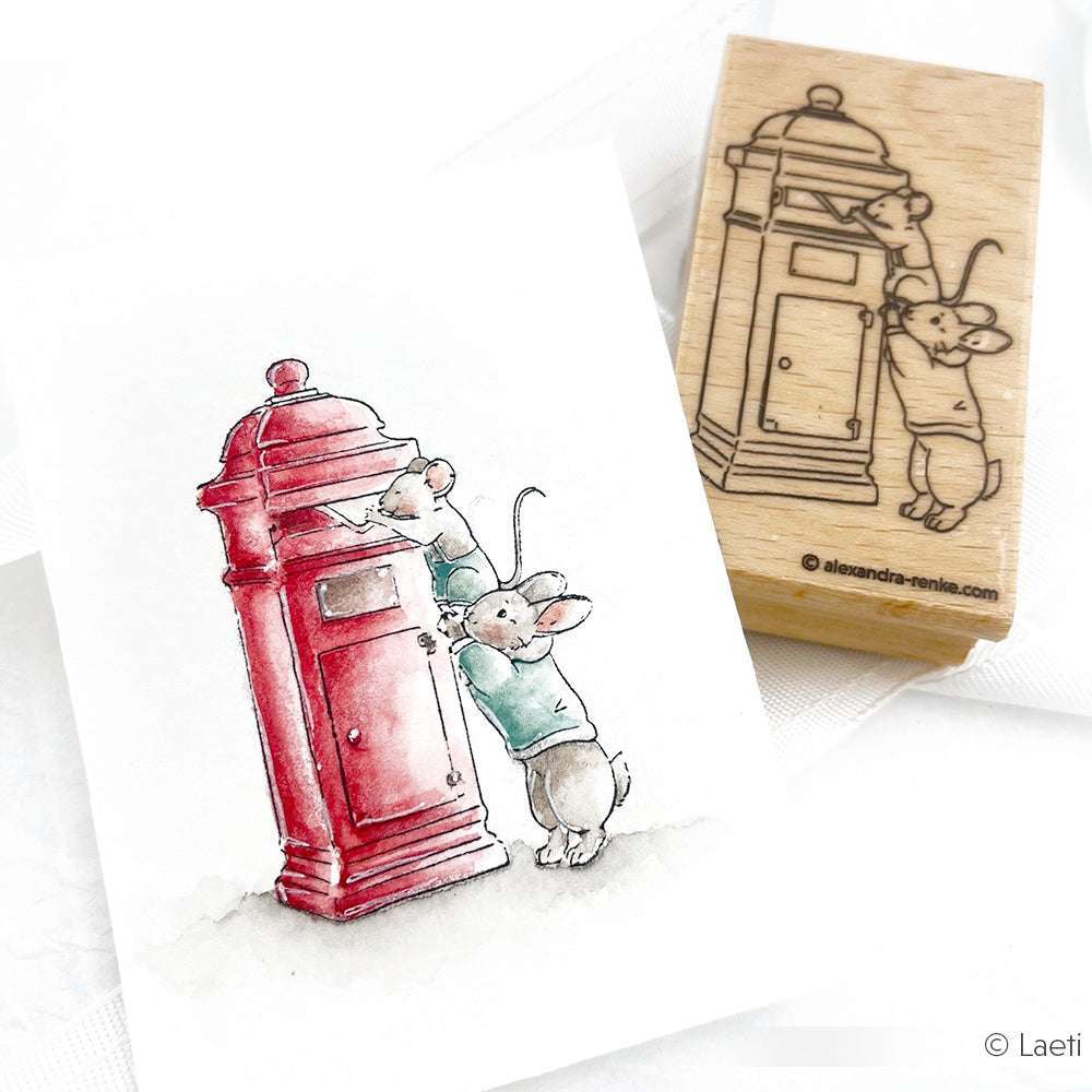 Zwei Mäuse werfen einen Brief in einen roten Briefkasten; die Szene von Alexandra Renke wird sowohl als Zeichnung als auch als Holzstempelabdruck gezeigt, perfekt für den Versand von Freudiger Weihnachtspost.
