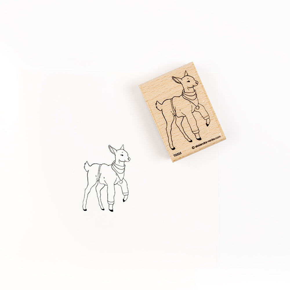 Ein Holzstempel, der ein Reh mit einem Schal darstellt, darunter ein Stempelabdruck.