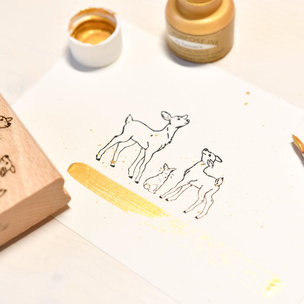 Stempelkunst mit zwei Rehfreunden auf Papier, akzentuiert mit metallischer Goldtinte und einem Holzstempel.