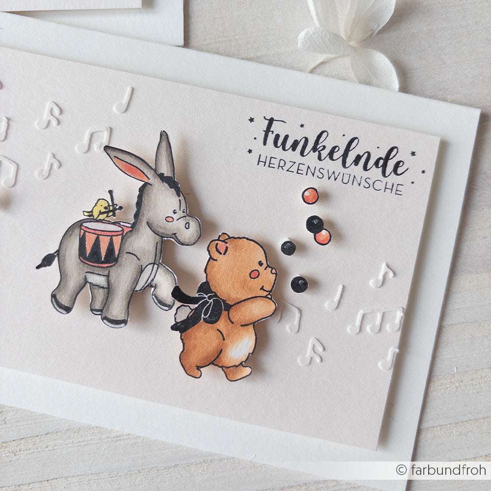 Illustrierte Karte von Alexandra Renke mit einem jonglierenden Bären, einem musizierenden Esel, Musiknoten und dem deutschen Text "Funkelnde Herzenswünsche".
