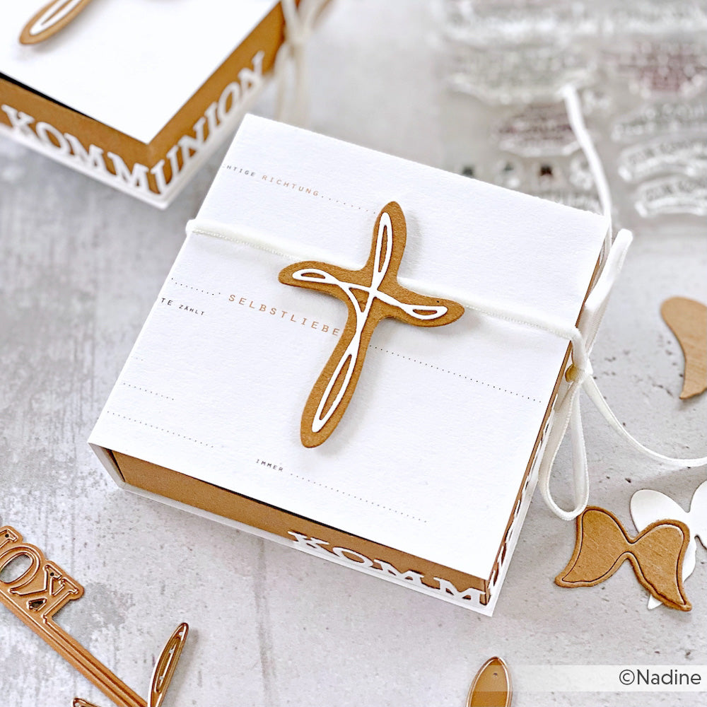 Weiße Geschenkbox mit einem braunen Kreuz aus Alexandra Renke Motivstanze Artist Kreuz, deutschem Text und weißer Kordel auf hellem Grund - ideal, um Ihre Lieblingskreationen von Alexandra Renke Designpapiere oder Stanzsysteme zu präsentieren.