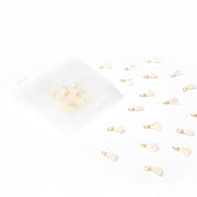 Kleine Tasseln Ivory mit goldenen Schlaufen von Alexandra Renke, einige verstreut und einige in einem durchsichtigen Beutel mit Reißverschluss - perfekte Akzente für Bucheinbände oder zarte Schmuckstücke.