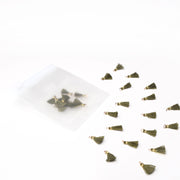 Alexandra Renke's kleine grüne Quastenanhänger mit goldenen Spitzen, ideal für Papierprojekte oder Buchbindearbeiten, werden neben einem halbtransparenten Reißverschlussbeutel auf einer weißen Fläche gezeigt.