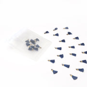 Kleine marineblaue Quasten von Alexandra Renke (Tasseln Königsblau) verstreut auf Weiß, einige in einem durchsichtigen Beutel - perfekt für Buchbindearbeiten oder Schmuck selber machen.