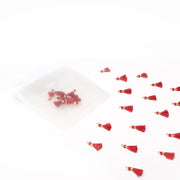 Die roten Tasseln Karminrot von Alexandra Renke sind neben einem durchscheinenden weißen Beutel auf weißem Hintergrund verstreut, ideal für Schmuck DIY oder Buchbinden Projekte.