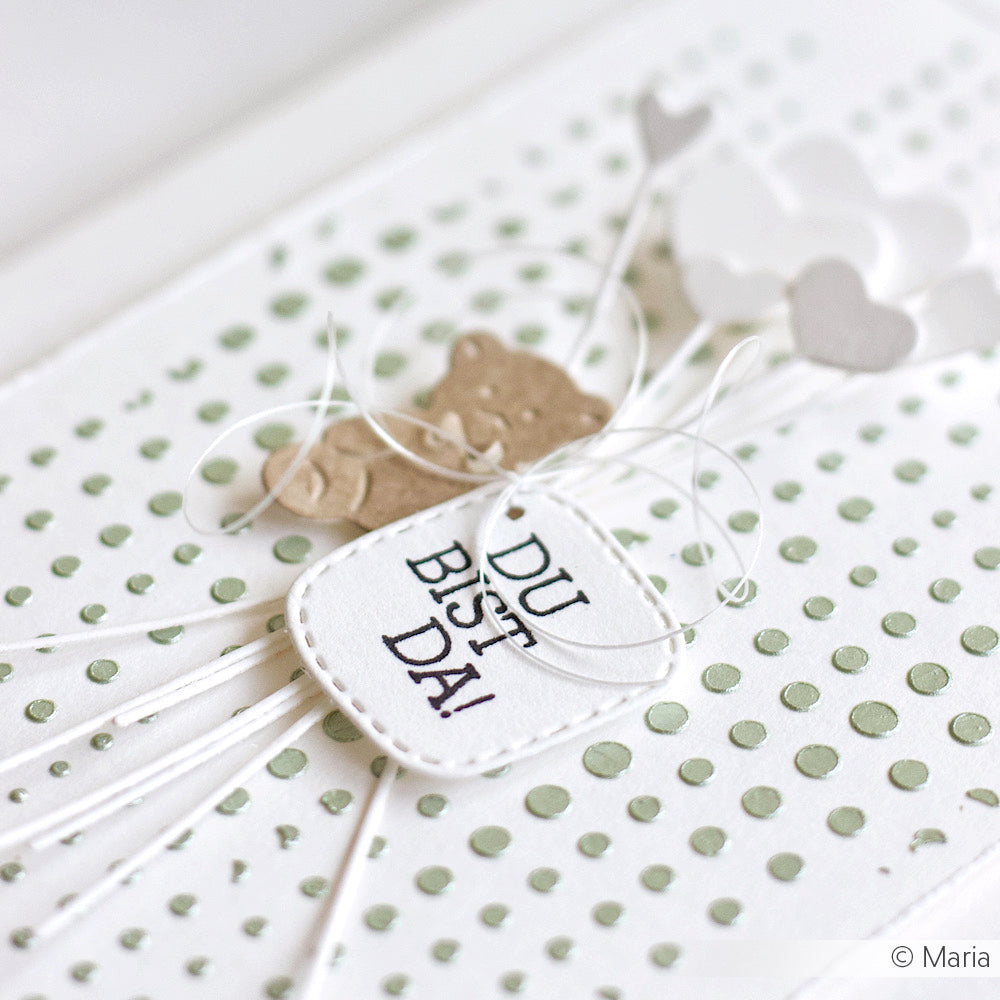 Handgemachte Karte von Alexandra Renke mit einem kleinen Bären, herzförmigen Luftballons und einem DU BIST DA! Anhänger auf gepunktetem Hintergrund - ideal, um Ihre Lieblingsmotive aus dem Clear Stamp Set Deutsch zu zeigen.