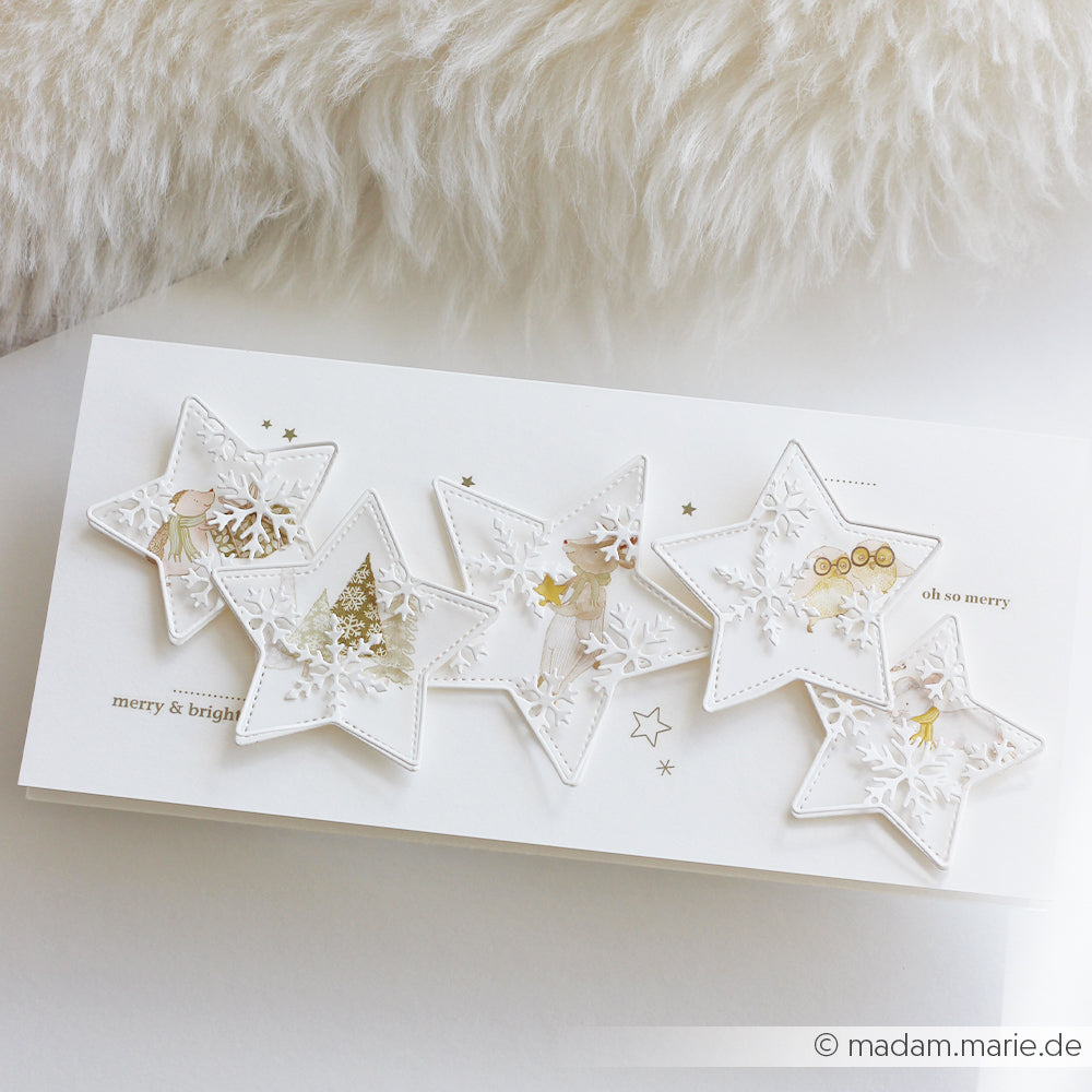 Handgefertigte Weihnachtskarte mit fünf sternförmigen Fenstern, Illustrationen und dem Rub-On-Schriftzug Frohe Weihnachten.