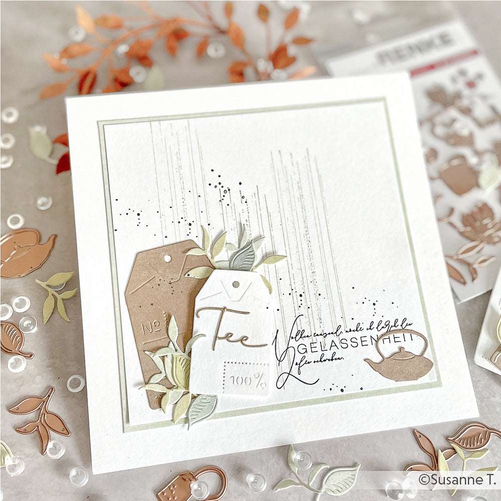 Handgemachte Karte von Alexandra Renke mit ausgeschnittenen Teebeuteln, Blättern und deutschem Text, erstellt mit einem Clear Stamp Set auf weißem Hintergrund, verziert mit verstreuten Bastelmaterialien.