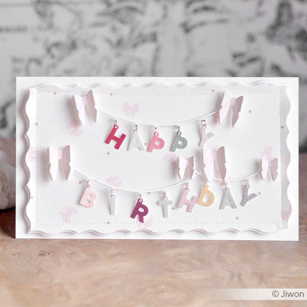 Handgefertigte Geburtstagskarte mit pastellfarbenen Buchstaben, die mit der Alexandra Renke Motivstanze ABC Anhänger ausgeschnitten wurden und an einer Schnur mit süßen Schleifen hängen.