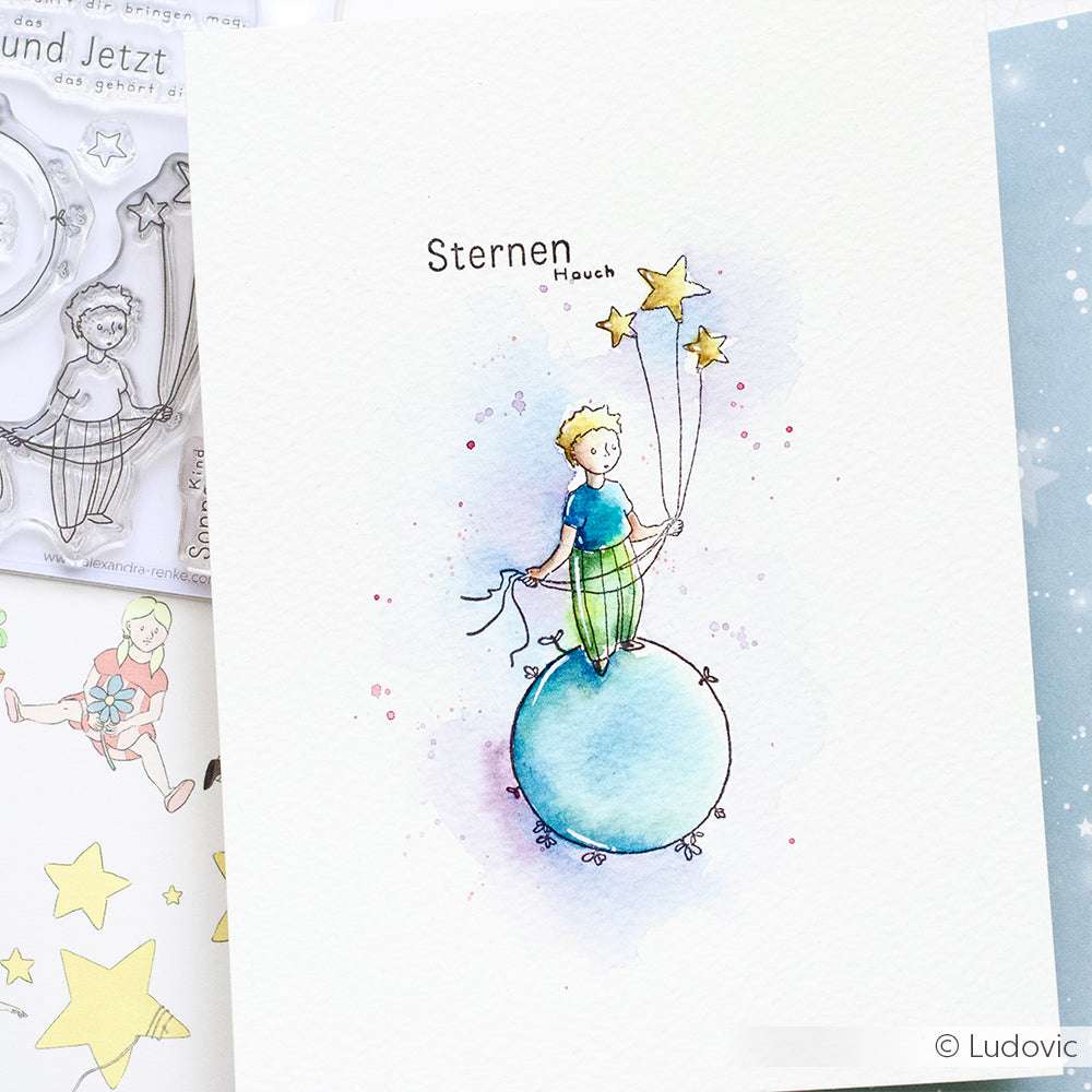 Ein aquarelliertes Kind auf einer blauen Kugel, das Sternenluftballons in der Hand hält, mit "Sternen Hauch" darüber - perfekt als Inspiration für Ihre nächsten Kreationen mit Alexandra Renke Photopolymer Stempel oder Clear Stamp Set.