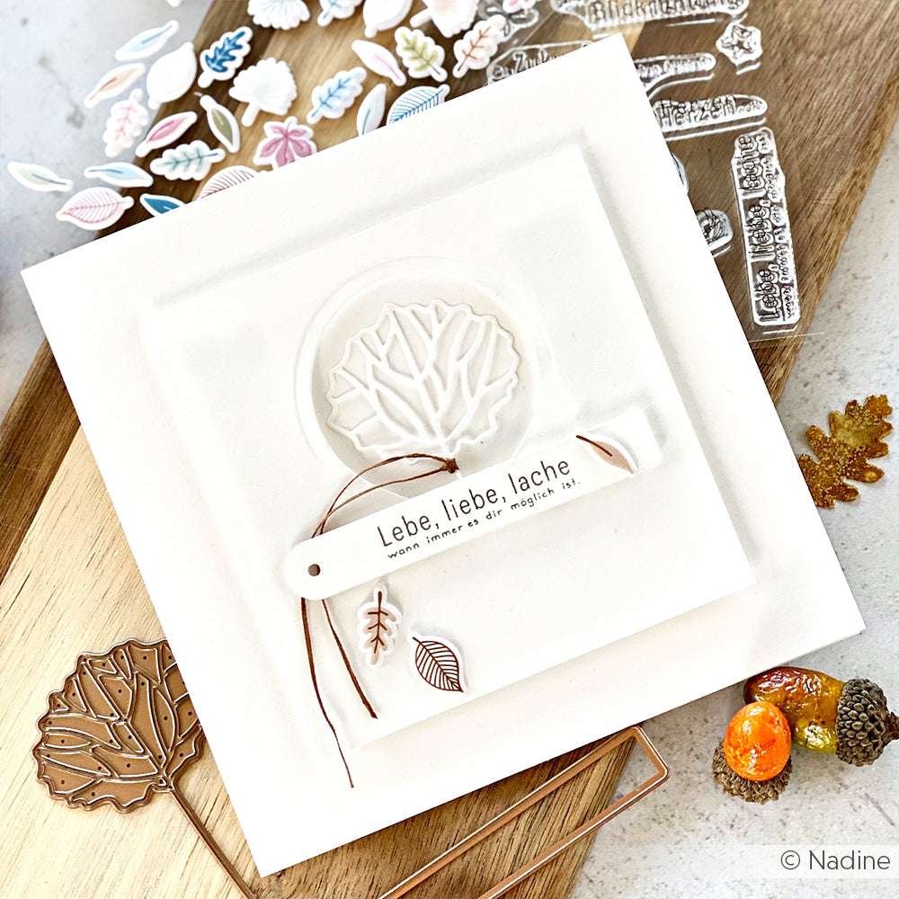 Eine handgefertigte Karte von Alexandra Renke mit einem Blattmotiv, deutschem Text und herbstlichen Details auf weißem Grund, hergestellt mit klaren Stempeln und einem Acrylblock für scharfe Abdrücke.