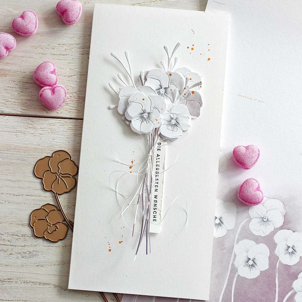 Eine weiße Alexandra Renke Karte mit handgefertigten Stiefmütterchen aus Designpapier, einer deutschen Botschaft und rosafarbenen herzförmigen Akzenten - ideal für kreative Papierprojekte.