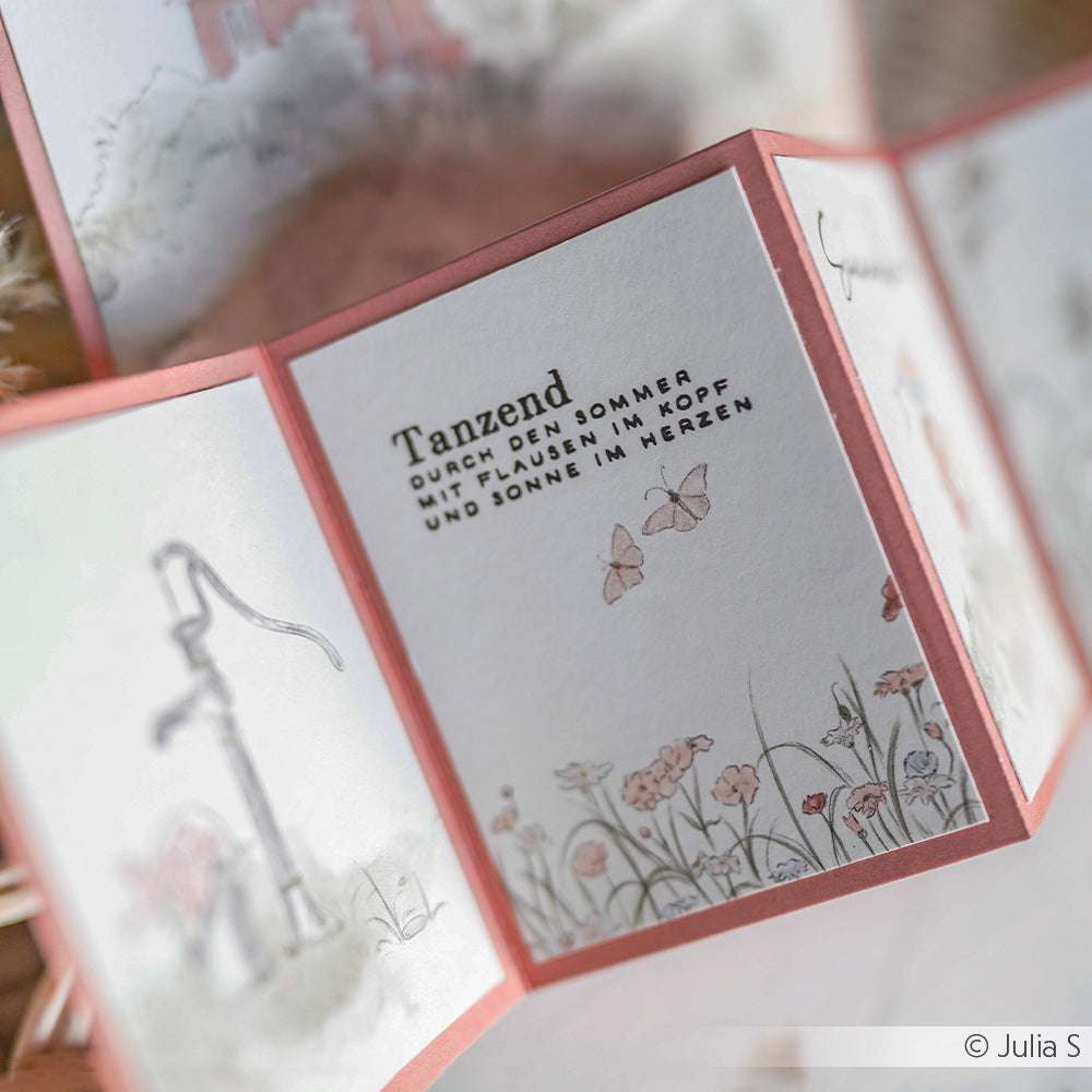 Eine Nahaufnahme einer Klappkarte mit floralen Illustrationen, die mit einem Klarsichtstempelset von Alexandra Renke hergestellt wurde, mit deutschem Text auf dem mittleren Feld.