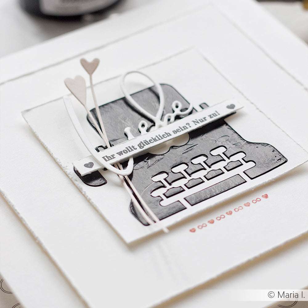 Handgefertigte Karte von Alexandra Renke mit schwarzer Schreibmaschine, Herzen und deutschem Text auf weißem Papier, hergestellt mit einem Clear Stamp für gestochen scharfe Details.