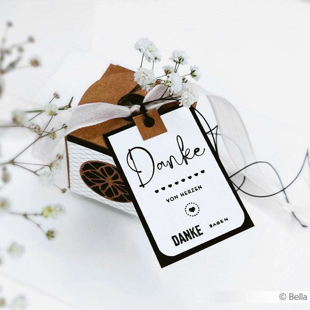 Geschenkbox von Alexandra Renke mit einem Danke-Schild mit Clear Stamp, weißem Band und kleinen weißen Blumen im Hintergrund. Mit Photopolymer- oder Klarsichtstempeln können Sie ganz einfach Ihre Dankbarkeit ausdrücken.