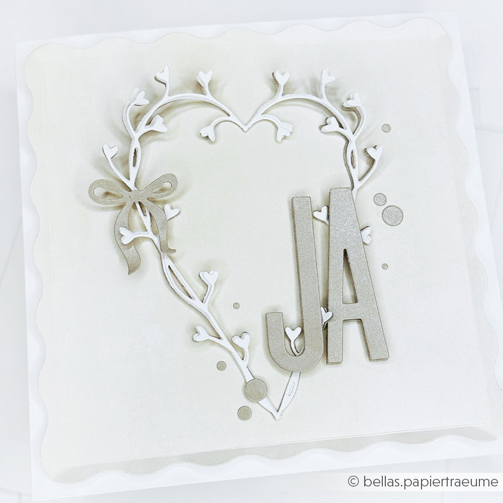 Weiße Hochzeitskarte mit herzförmiger Ranke, Schleife und großem silbernen "JA", gestaltet mit der Motivstanze Schmales Alphabet von Alexandra Renke und hochwertigen Designpapieren für ein elegantes Finish.