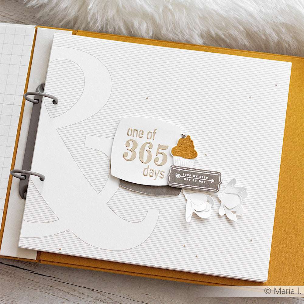 Scrapbook-Seite mit dem Text "Einer von 365 Tagen", einem Kack-Emoji und weißen Papierblumen auf weißem Hintergrund, die mit Alexandra Renke Photopolymer-Stempel für knackige Akzente gestaltet wurden.