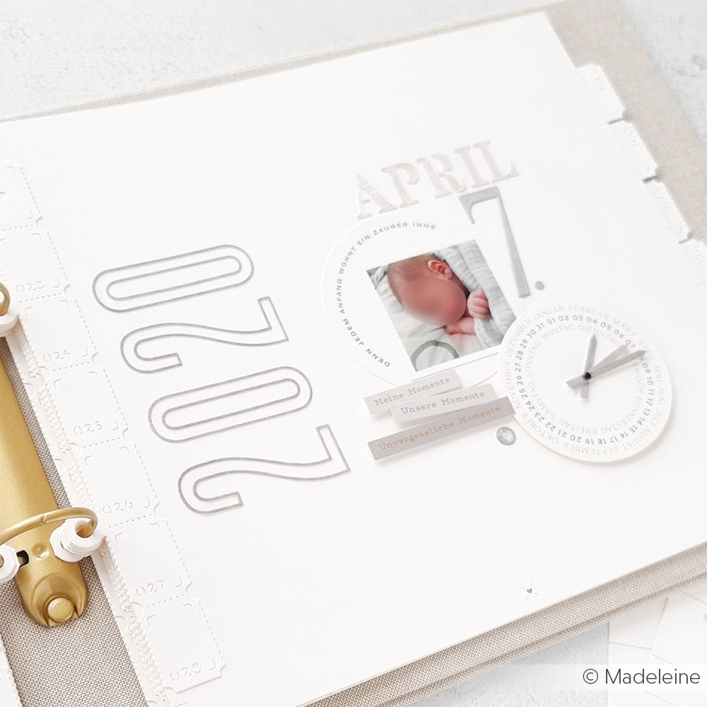 Scrapbook-Seite mit Alexandra Renke Designpapieren, datiert auf den 7. April 2020, mit einem Babyfoto und einer kleinen Papieruhr, die auf 3:00-Zahlen eingestellt ist und mit der Motivstanze Schmale Zahlen Outline erstellt wurde.