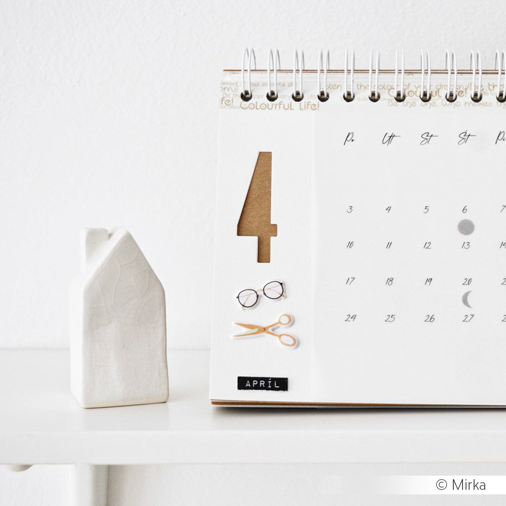 Minimalistischer April-Kalender auf einem weißen Regal mit einem kleinen Keramikhaus, Gläsern und einer Schere - gestylt mit Alexandra Renke Stanzsysteme und der Motivstanze Schmale Zahlen Outline für einen kreativen Touch.