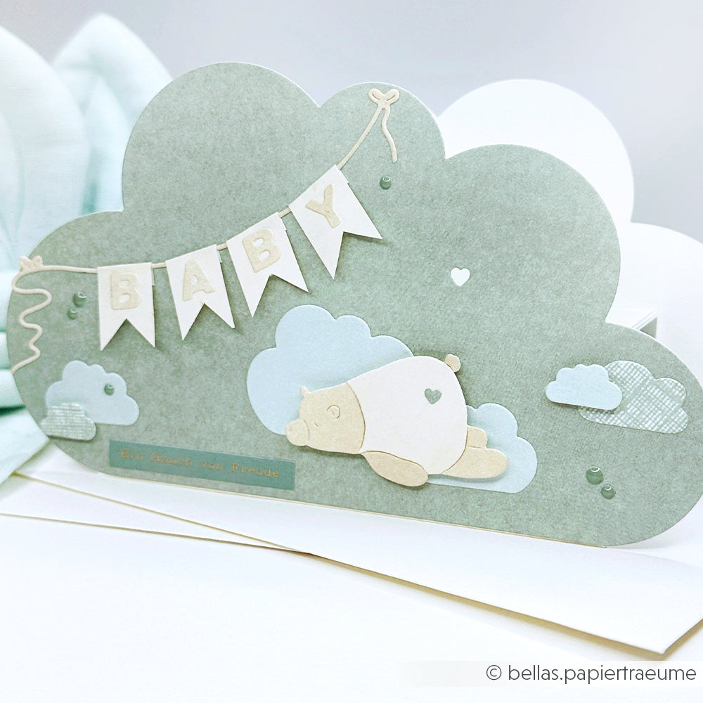 Wolkenförmige Babykarte von Alexandra Renke mit BABY-Wimpeln, einem schlafenden Bären und pastellblauen Wolkenakzenten, hergestellt mit Motivstanze Blockbuchstaben auf süßem Designpapier.