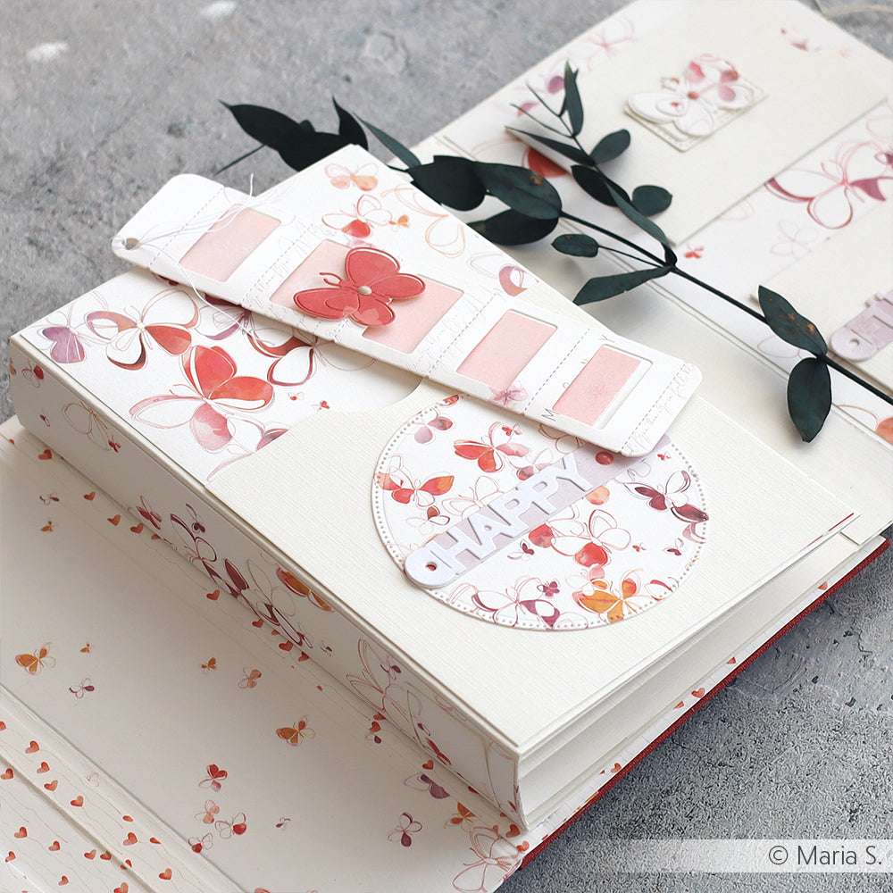 Ein handgefertigtes Scrapbook von Alexandra Renke mit Schmetterlingsmotiven, botanischen Akzenten und einem HAPPY-Etikett auf einem kreisförmigen Happy Together"-Etikett, das mit filigranen Stanzformen hergestellt wurde und zusätzlichen Charme versprüht.